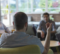 one person leading a group discussion with a few others listening intently while they go over the monthly forum