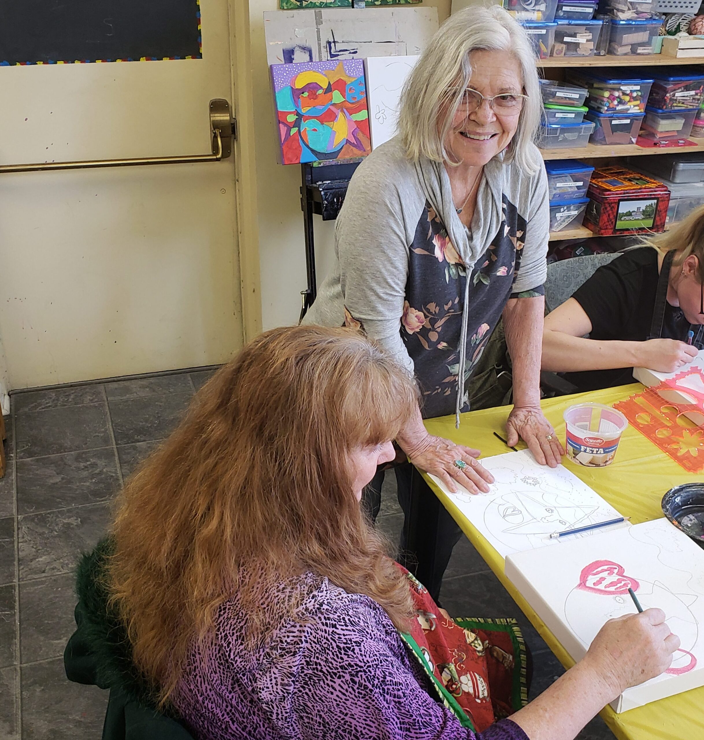 two artists paint or draw in the CMHA's wellness developments center with supervision from another artist