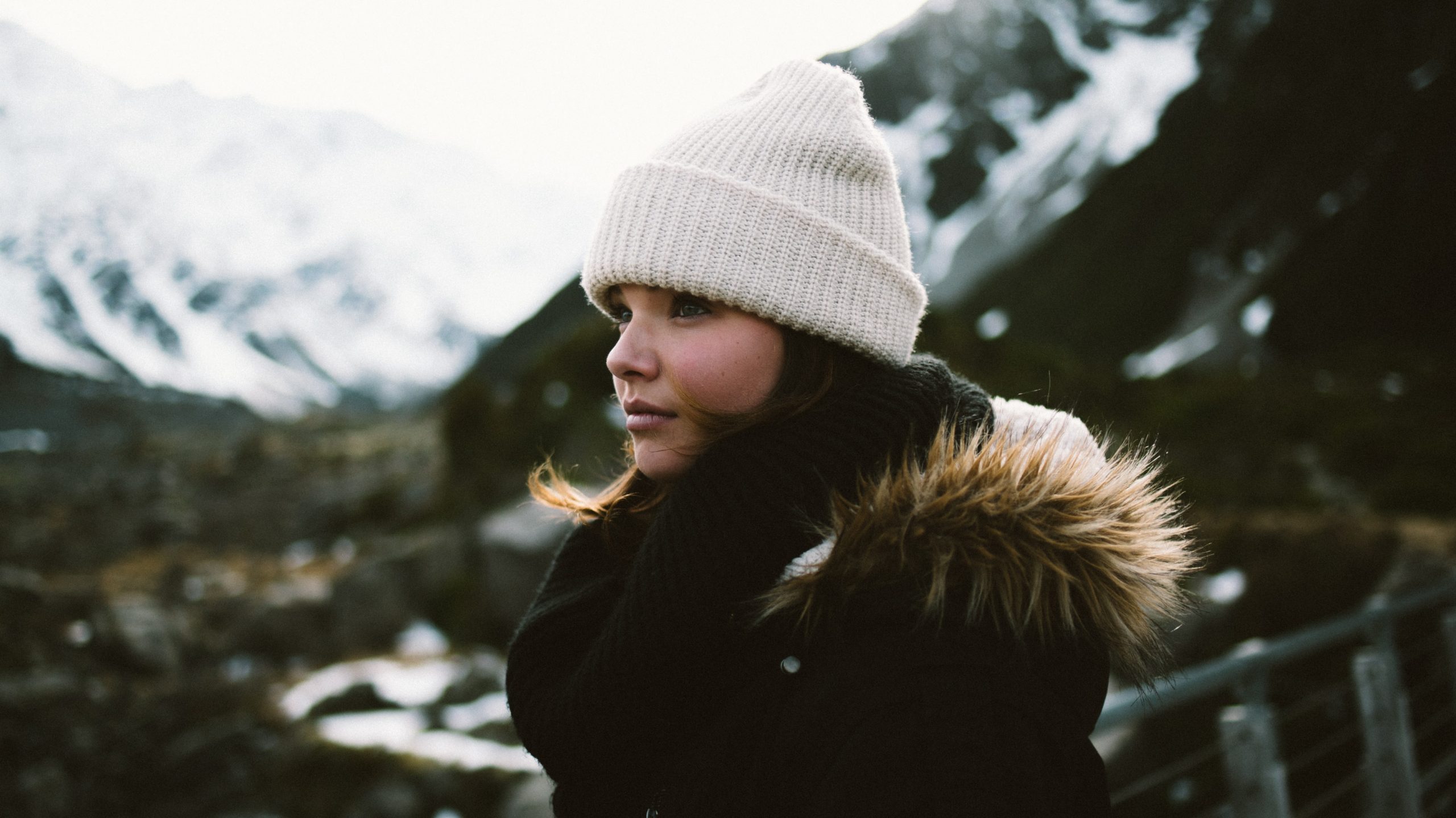 Woman outdoors in the mountains during winter staring off into the distance enjoying the moment and her mental health