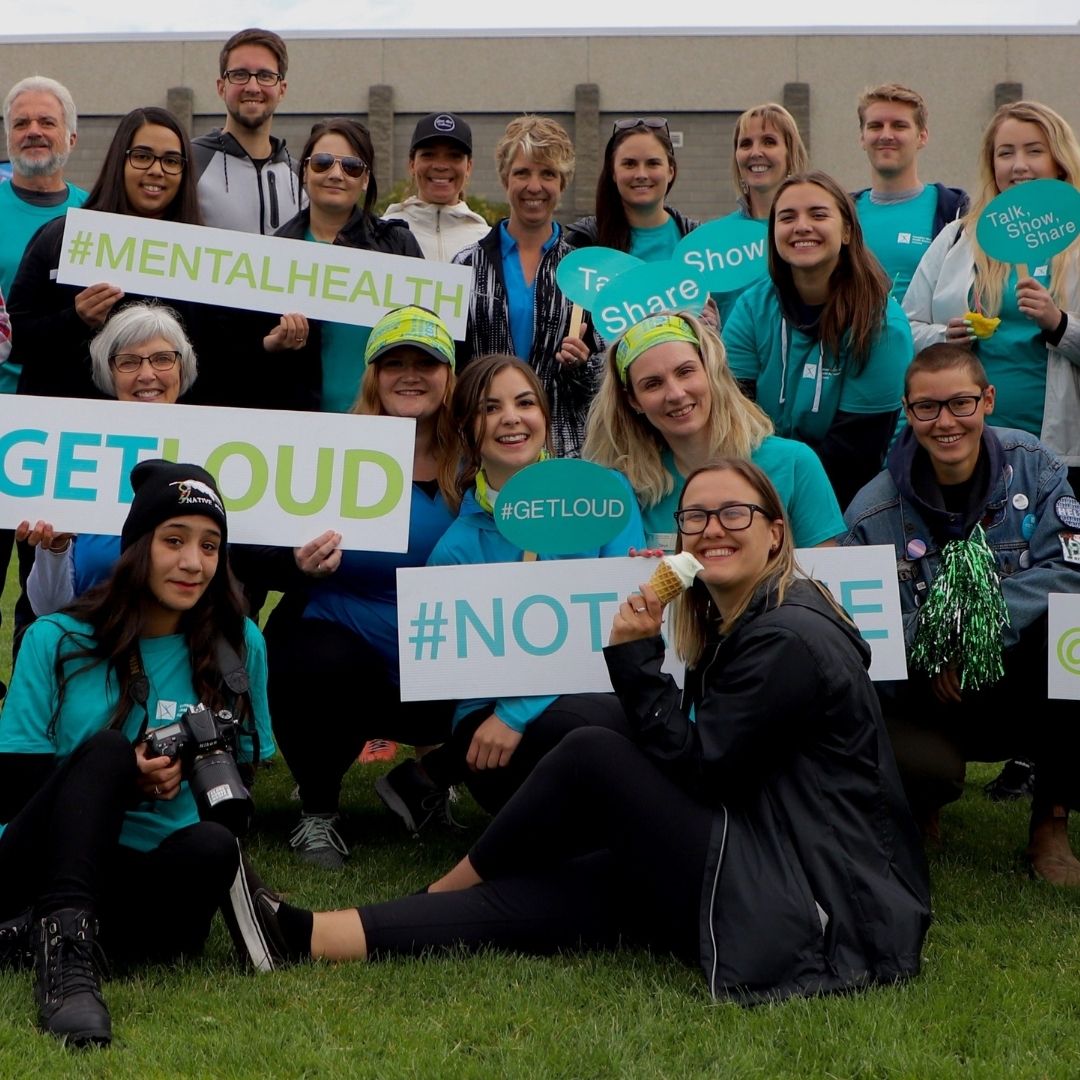 Group volunteer photo for # Get Loud for mental health everyone wearing CMHA blue get loud shirts and lots of signs for mental health
