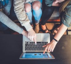 Online education, 3 people pointing to a screen educating themselves and each other in a little community of their own
