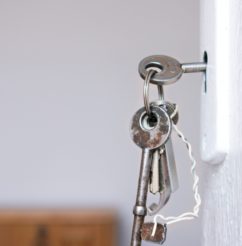 Keys handing from a door lock symbolizing "Building homes", a core value of CMHA Kelowna