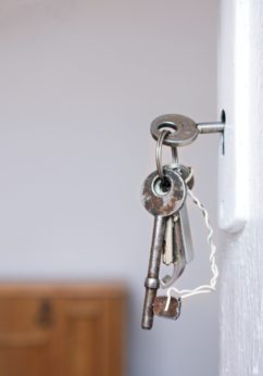 Keys handing from a door lock symbolizing "Building homes", a core value of CMHA Kelowna